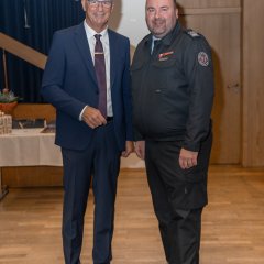 Gemeinde Brandinspektor Björn Steinebach (rechts), in einer Feuerwehruniform und Bürgermeister Winfried Steinmacher (links) in einem dunklem Anzug mit weißem Hemd und Brille.