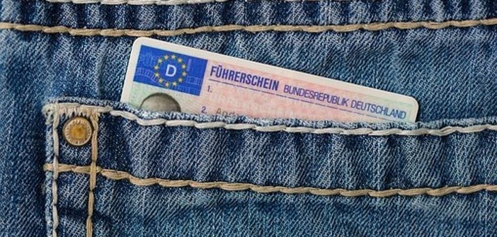 In einer Jeans-Hosentasche steckt die  blau-rosa-beige Führerscheinkarte der BRD