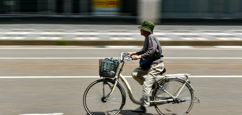 Auf einer autofreien Straße fährt ein Mann mit Hut auf einem Fahrrad.