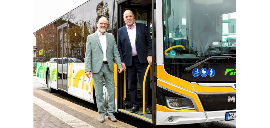 Personennahverkehrbus mit grüner und gelber Folie und weißen Buchstaben RTV mit Andreas Remler, Geschäftsführer der RTV und Arno Brandscheid, Vorsitzender der Geschäftsführung der RTV.