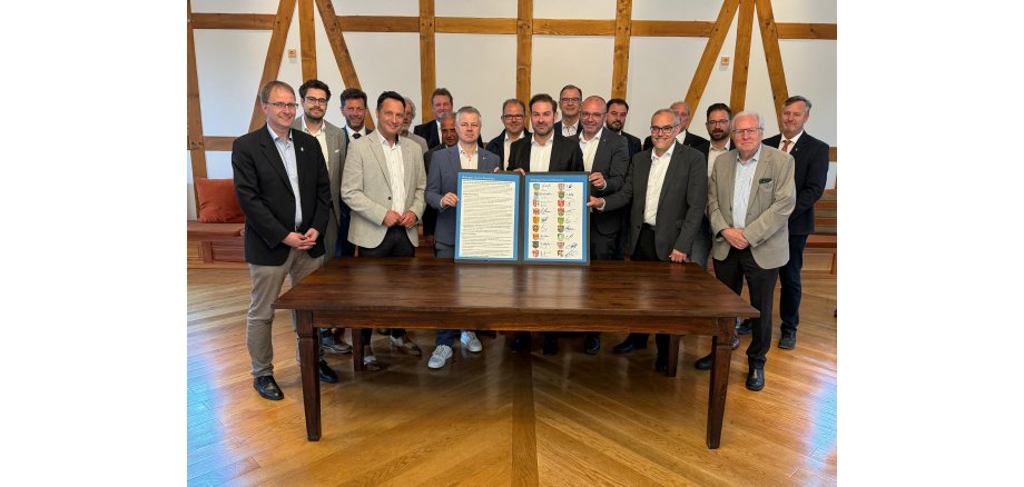 Hinter einem Holztisch stehen die Bürgermeister des Rheingau-Taunus-Kreises und halten die unterzeichnete Resolution in der Hand.